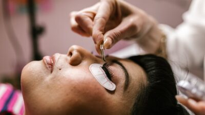 Close-up van een vrouw die in een beautysalon met een pincet wimperextensions laat plaatsen
