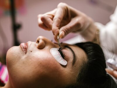Close-up van een vrouw die in een beautysalon met een pincet wimperextensions laat plaatsen