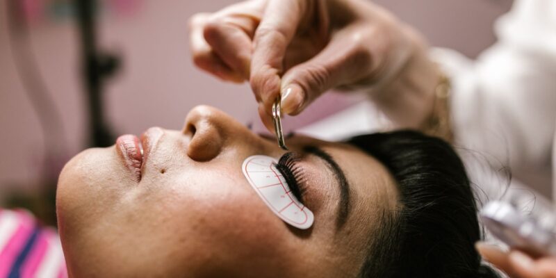 Close-up van een vrouw die in een beautysalon met een pincet wimperextensions laat plaatsen